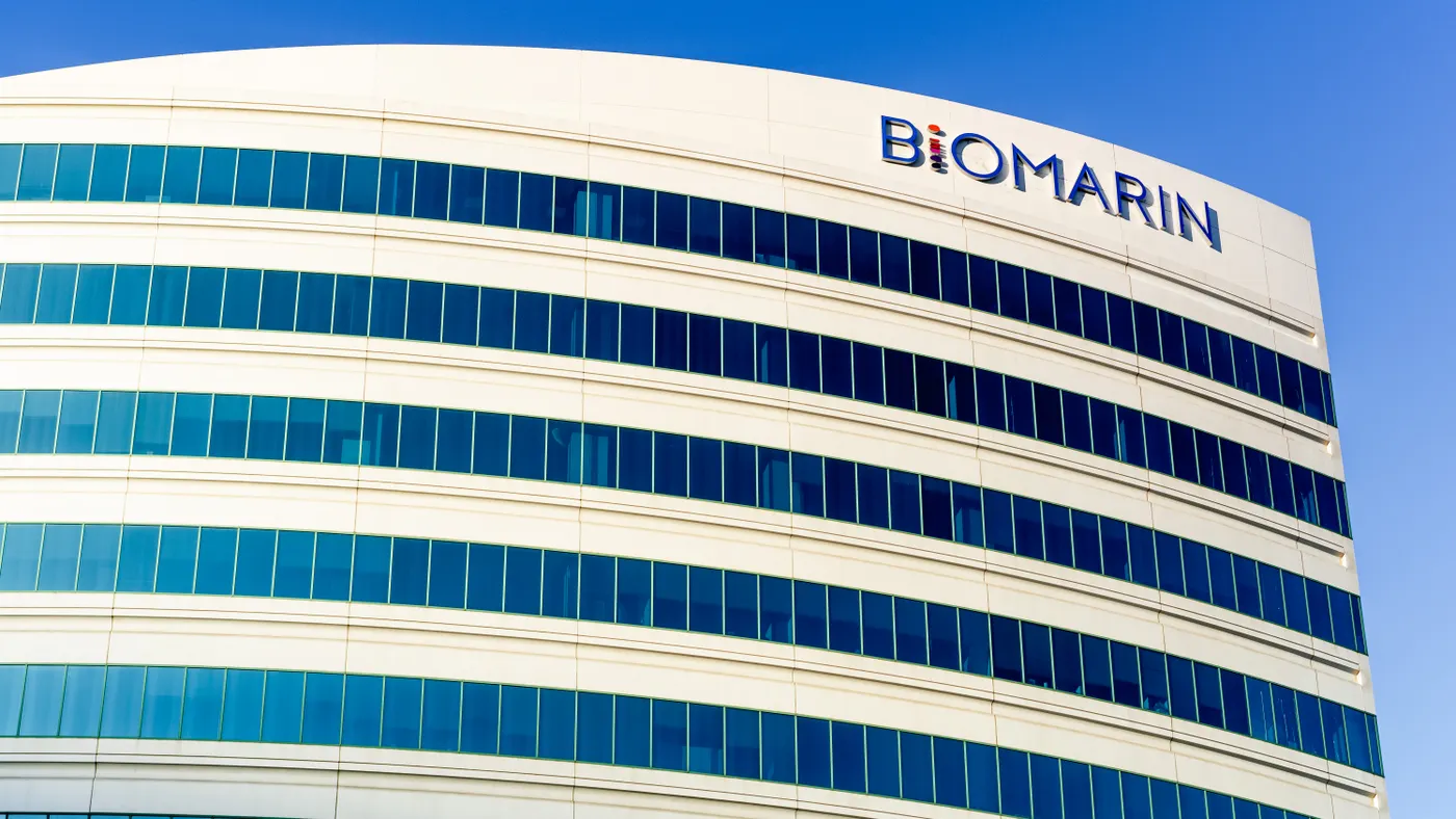 A white office building bearing a sign for BioMarin Pharmaceutical stands against a blue sky.