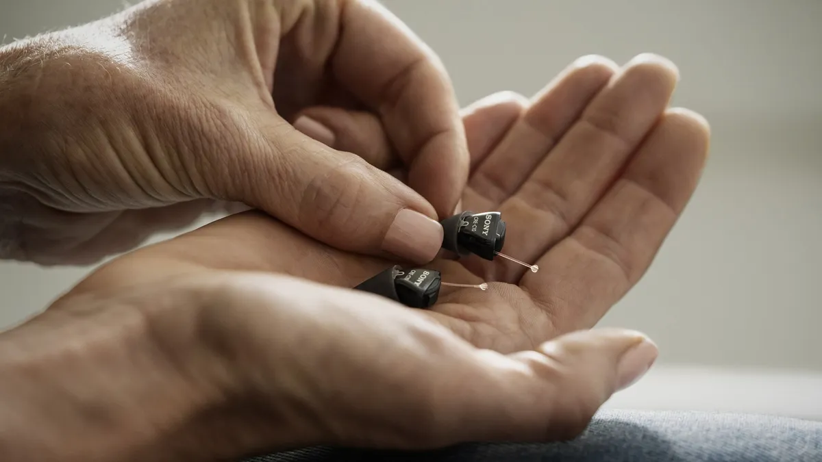 Sony's new over-the-counter hearing aids in the palm of a man's hand.