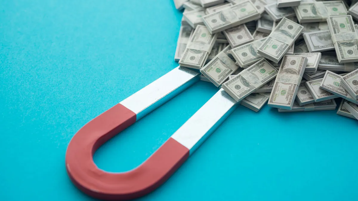 Horseshoe magnet attract heap US dollar bill banknotes on blue background.