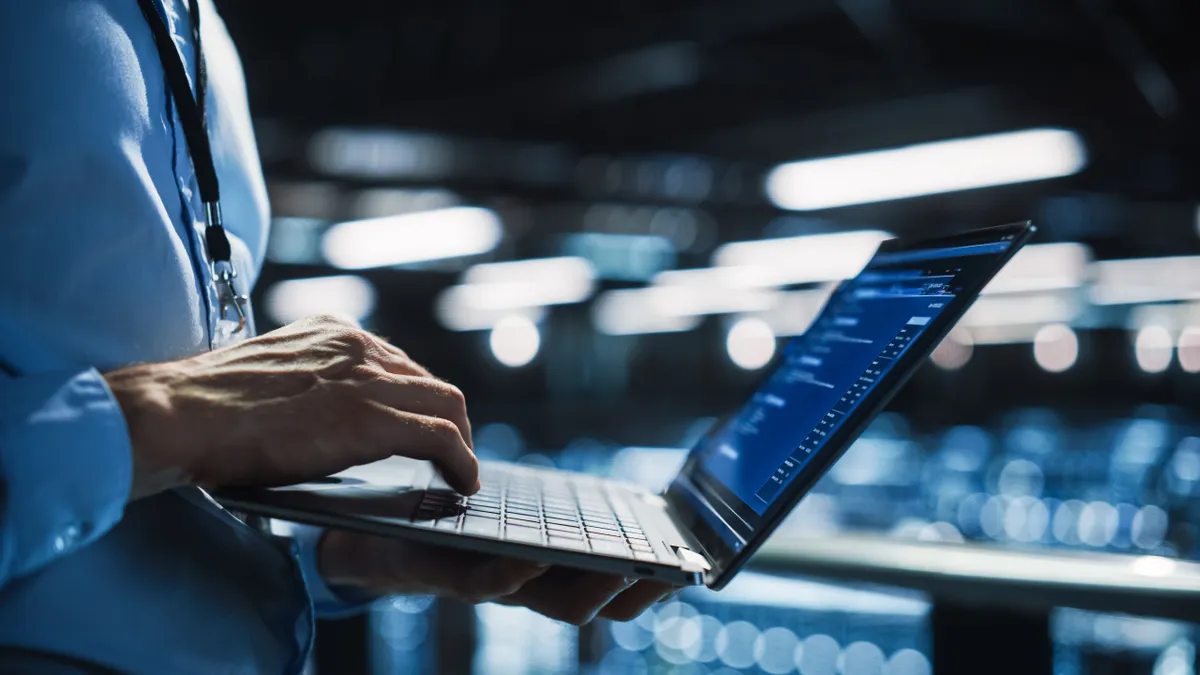 an IT worker in business attire holding a laptop