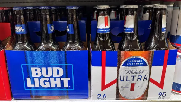 Two six packs of Bud Light and Michelob Ultra are next to each other on a store shelf.