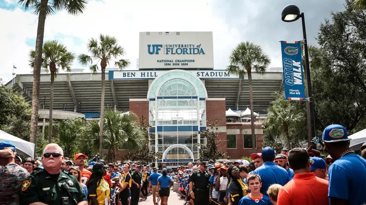 A large crowd gathers outside of a football stadium.