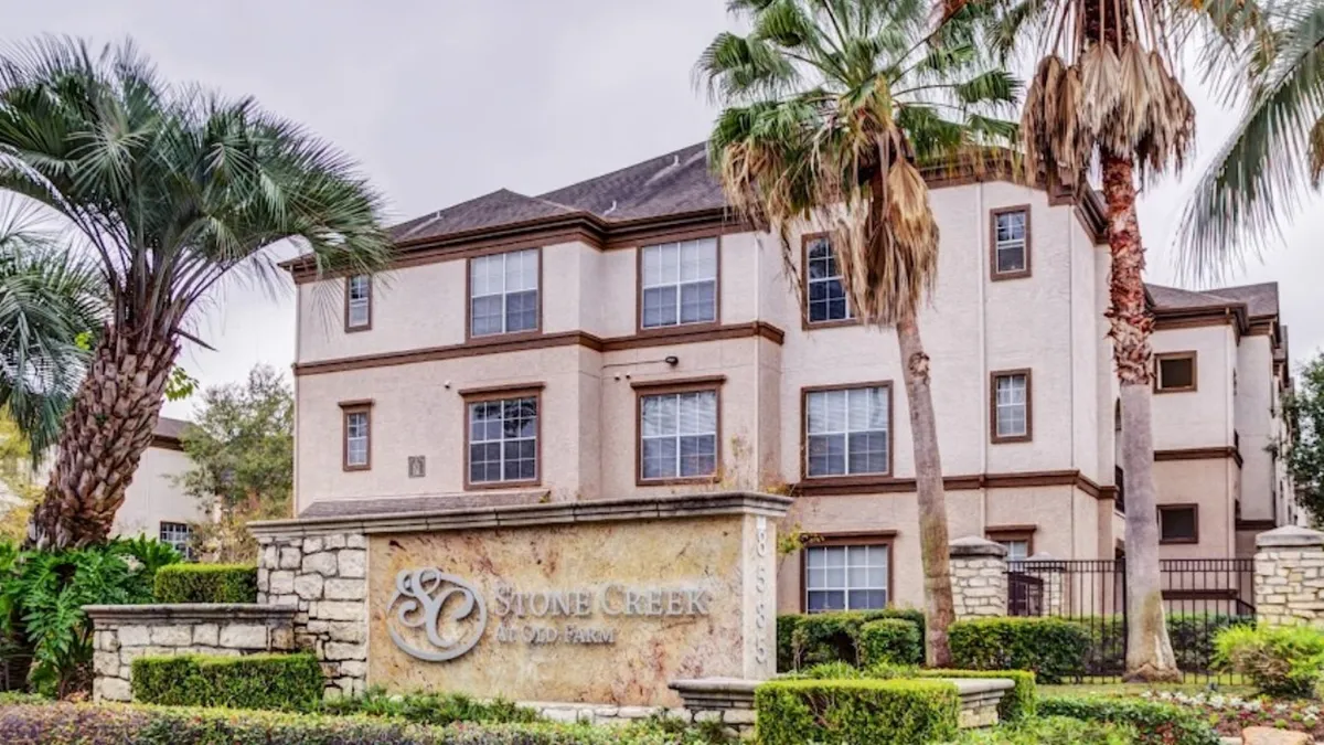 Tan three-story apartments with palm tree in the foreground