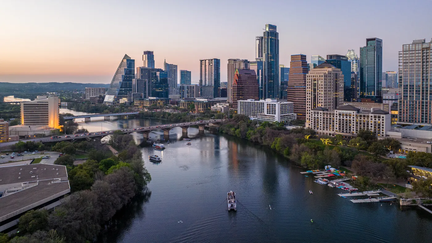 An aerial view of a city skyline at sunset over a river.