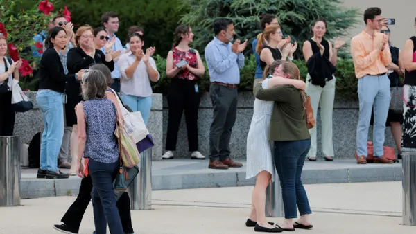 Employees clap for laid-off co-workers as they exit the building.