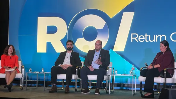 A photo of several people sitting on a stage addressing a group of people.