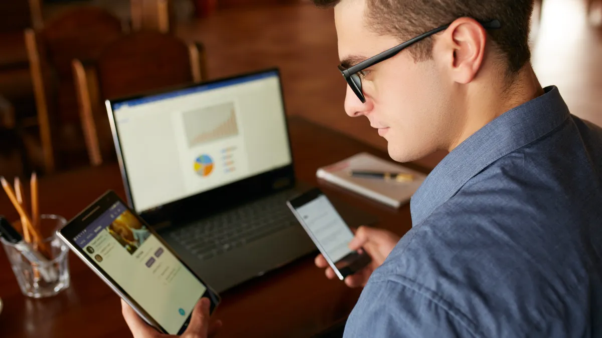 A man checks his phone and computer at the same time