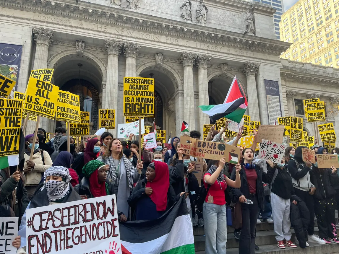 High school students stand near Bryant Park in New York City, holding up protest signs