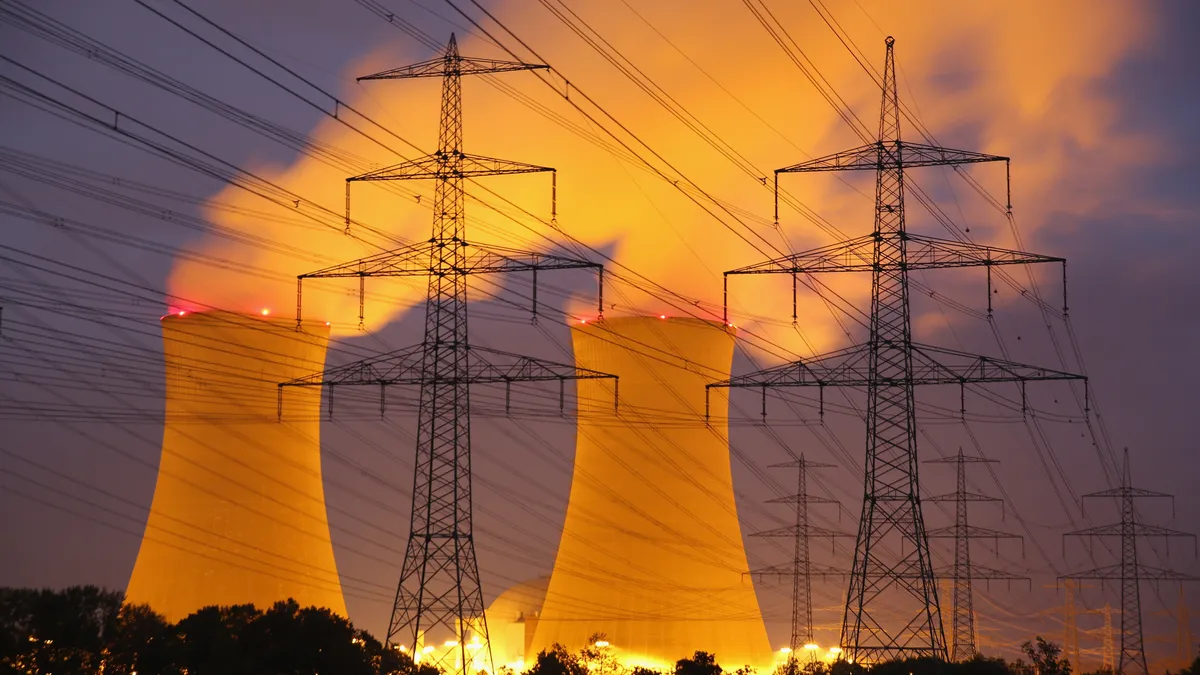 A nuclear plant stands behind transmission lines at night.