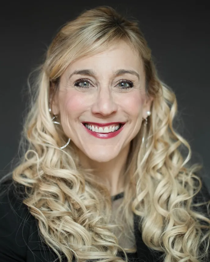 Headshot of a smiling woman with long blond hair wearing a black top.