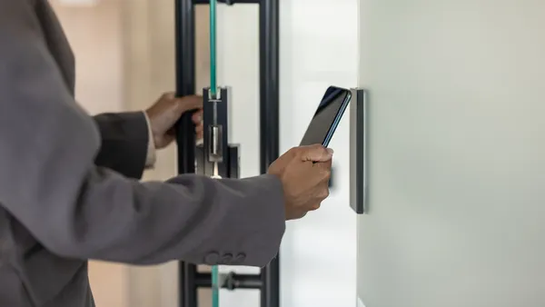Business professional using smartphone for secure access to modern office building.