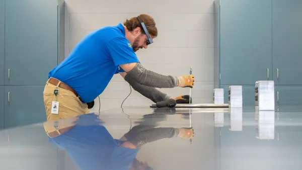 A person wearing an augmented reality headset uses calipers in an industrial facility.