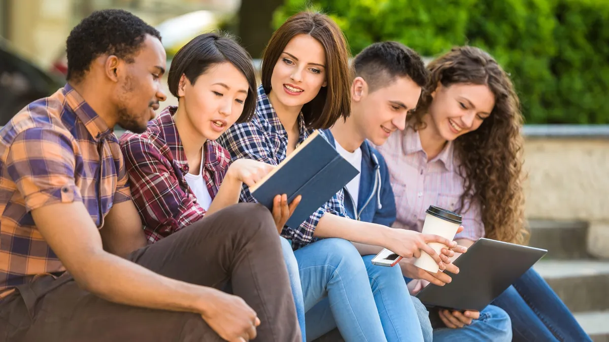 Group of young smiling students dressed casual sitting on the staircase outdoors on campus at the university.