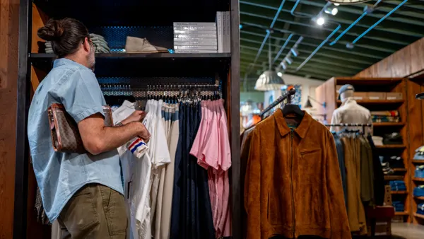 A consumer browses shirts at a retail store.