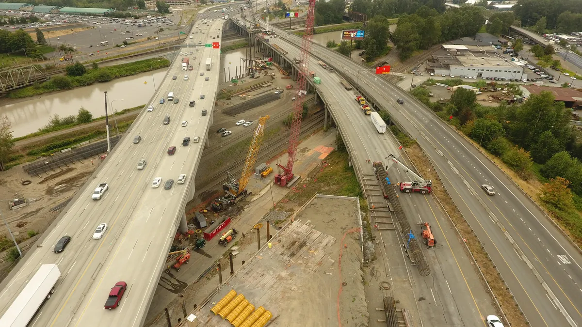 Aerial view of construction on a double-lane highway stretching over other roads and a river.