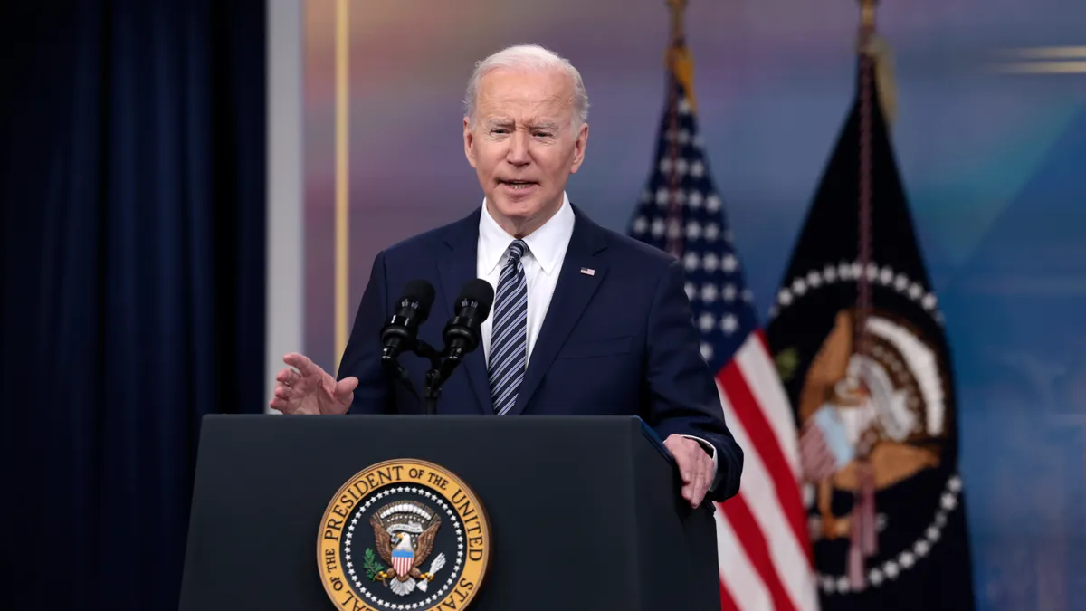 President Biden stands behind a lectern featuring the presidential seal.