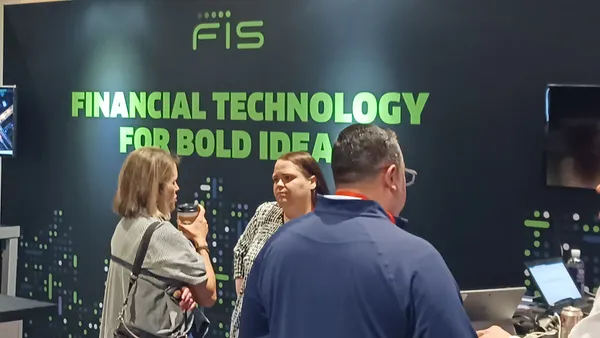 People standing at a booth in front of a conference booth with a placard that says 'FIS.'