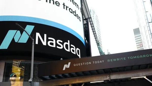 Nasdaq logo and signage on the curved exterior of its MarketSite building, viewed from street level.