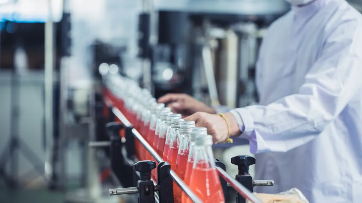 A worker checks a row of bottled juices.