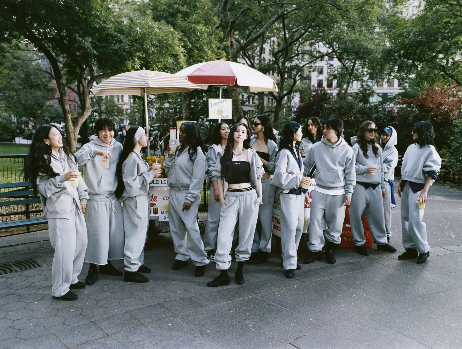 A group of people in grey sweatpants and hoodies at an outdoor food stand.