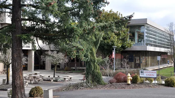 Modern brutalist building with picnic tables outside in foreground.