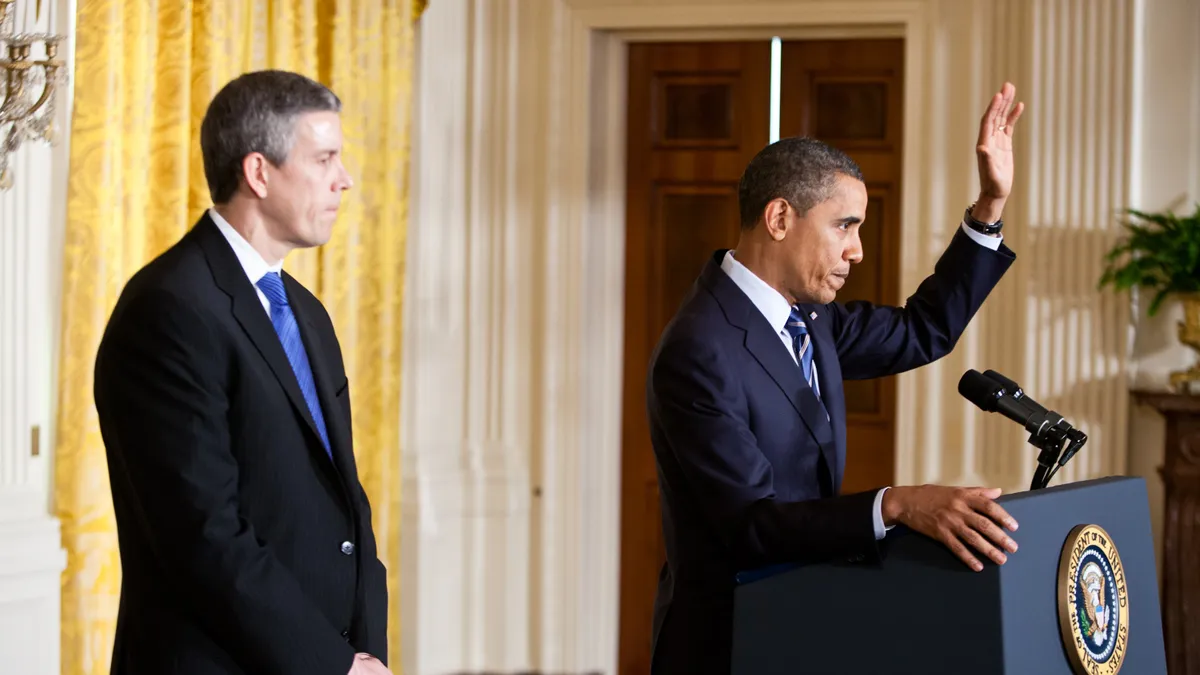 President Barack Obama, joined by Education Secretary Arne Duncan, stands at a podium to deliver remarks at the White House.