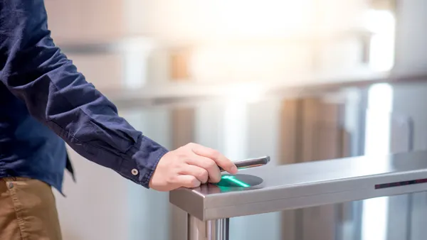 An employee uses a smartphone to open an automatic gate at an office.