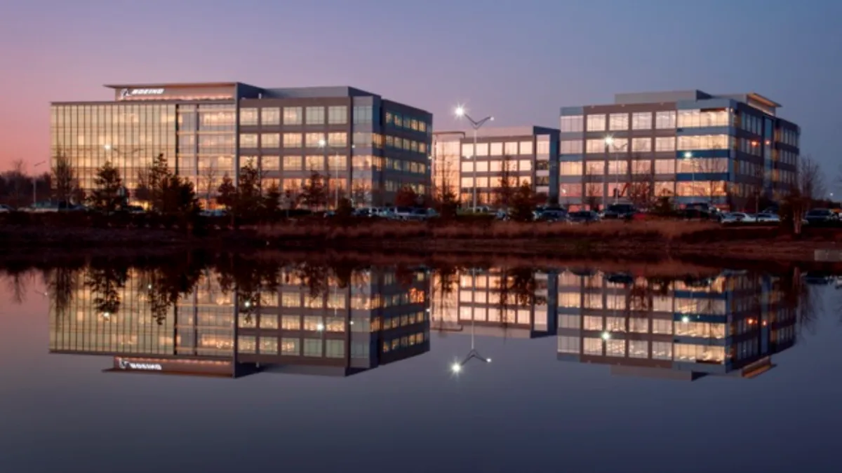 A building with glass windows, with a body of water reflecting off of it.