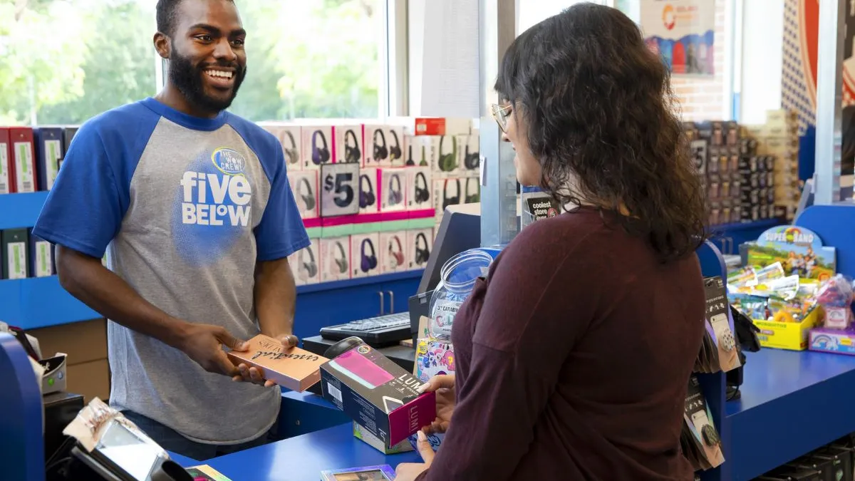 A Five Below employee assists a customer at the checkout counter