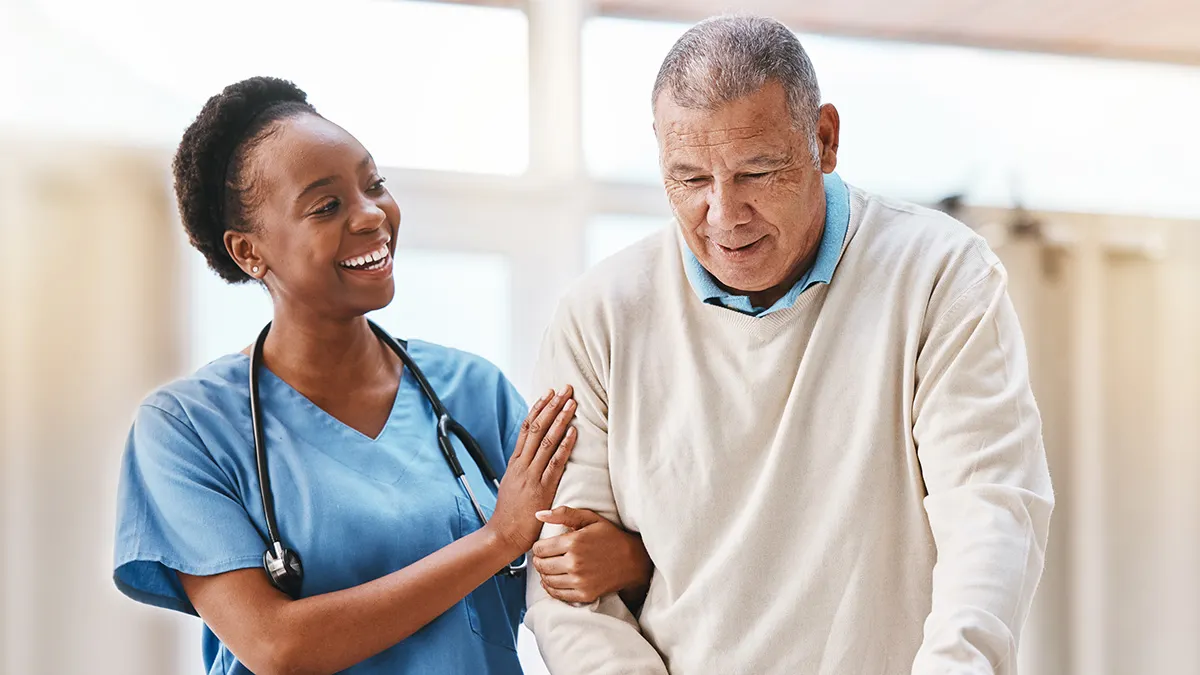 Medical nurse supporting an elderly person walking with a cane.
