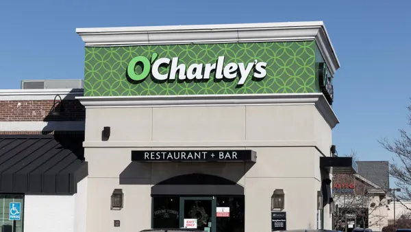 A photograph of a corner restaurant with beige paint and a green sign that says O'Charley's