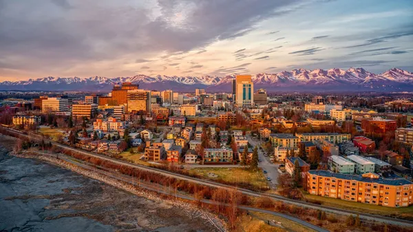 An aerial view of a city with snow-covered mountains behind it.