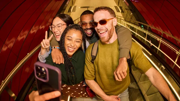 A group of friends take a selfie on the top of an escalator