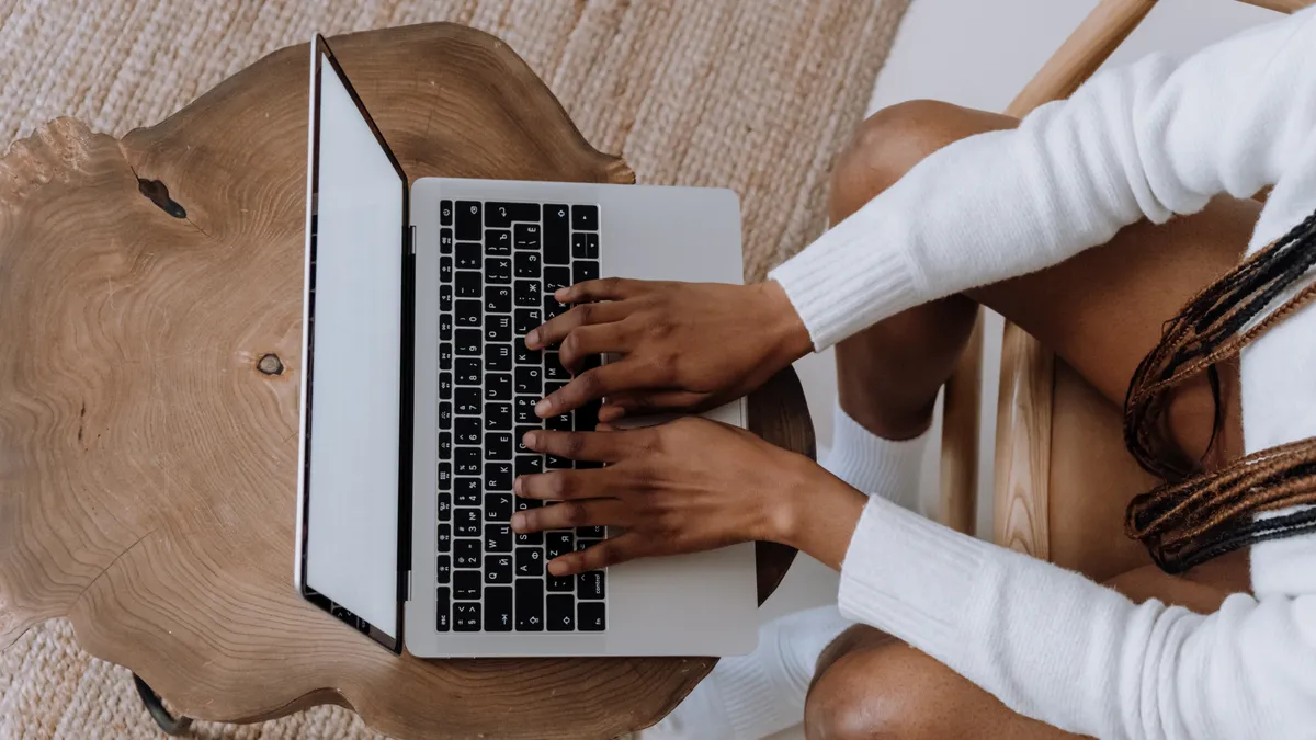 A Black person types on a laptop