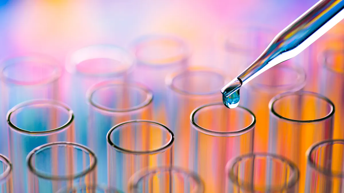 A droplet from a pipette hangs over a series of test tubes in this stock image.