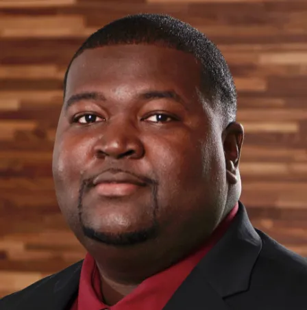 Man in red shirt, dark jacket and tie.