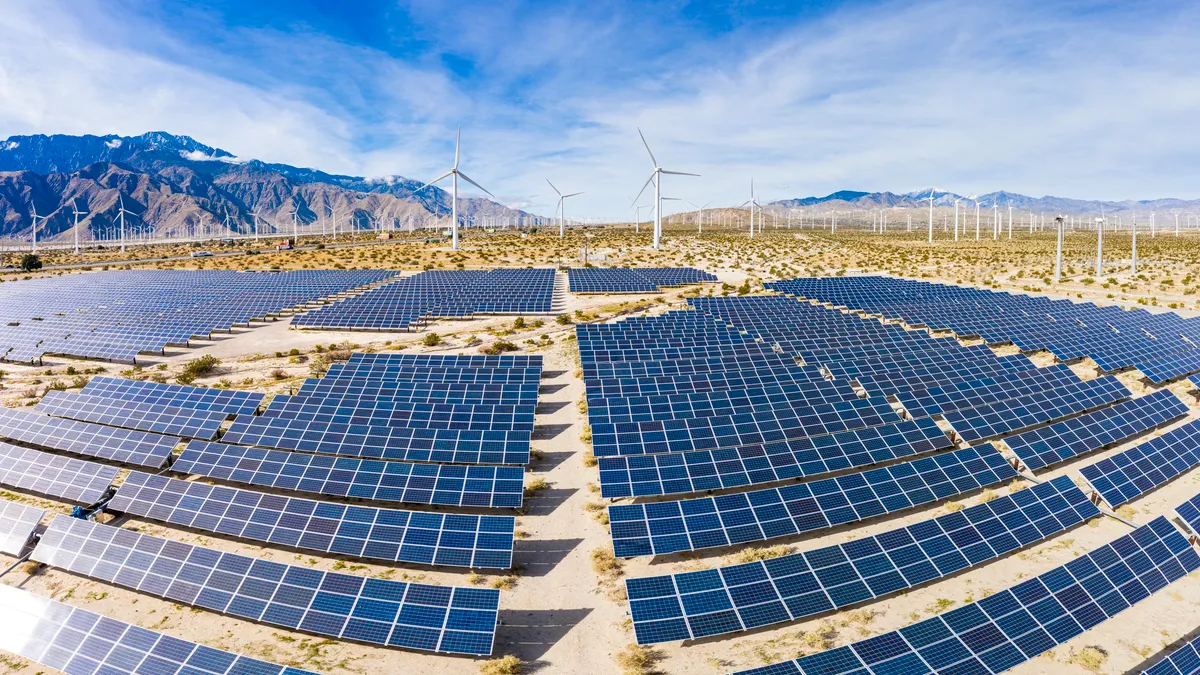 A field of solar panels and windmills in the desert.