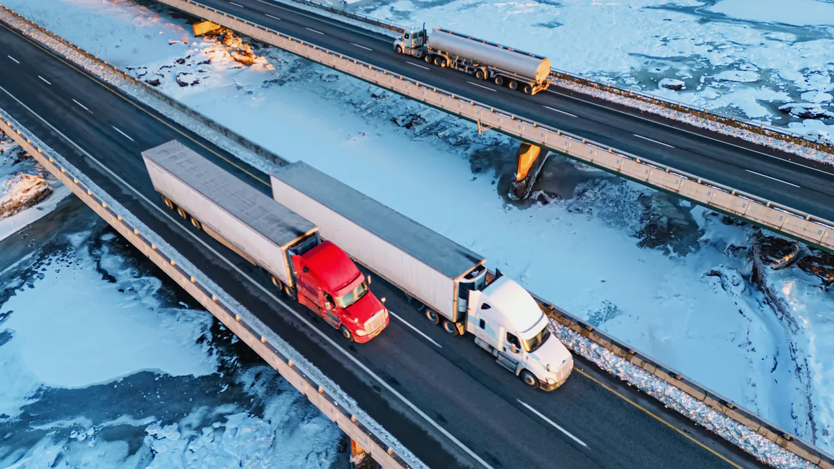 Aerial view of semi trucks crossing a frozen tidal river.