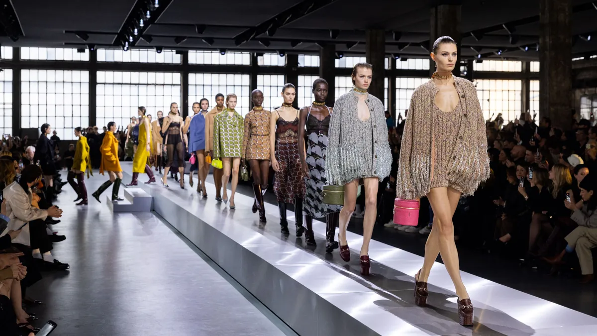 Models walk on a runway in an airy atelier.