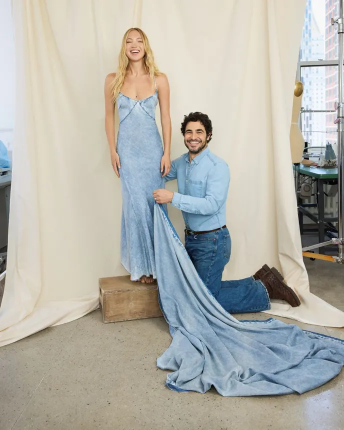 A model stands on a piece of wood modeling a dress from the GapStudio summer collection while designer Zac Posen stands next to them.