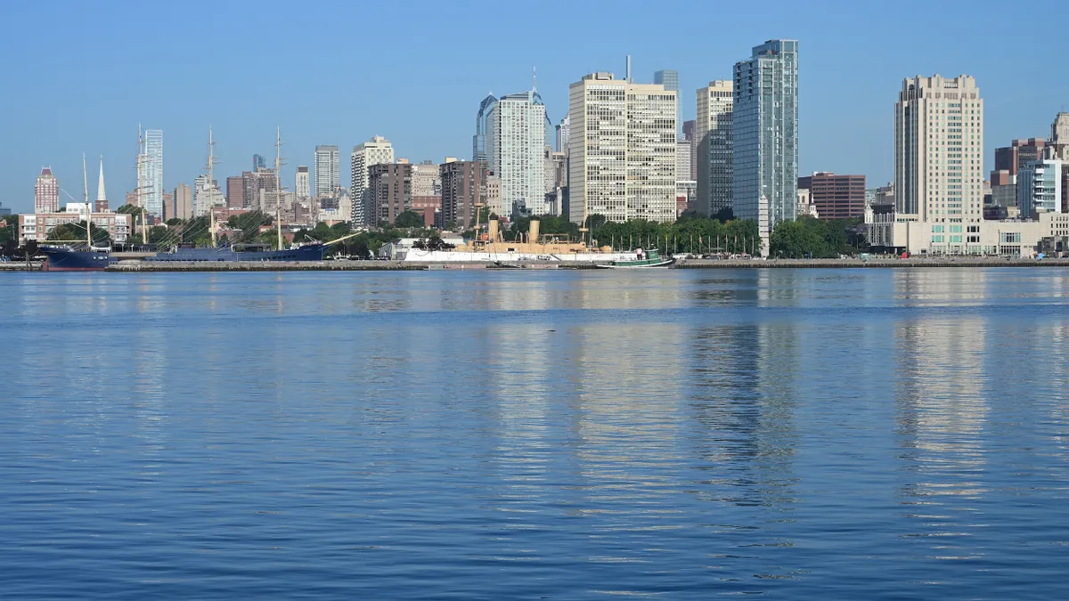 Tall buildings along a coast with large body of water in foreground.