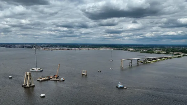 Several barges float around the wreckage of a bridge.