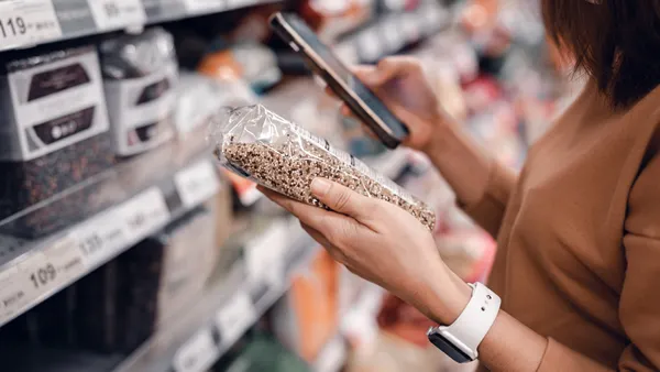 Woman shopping in supermarket and reading product information. Costumer buying food at the market.