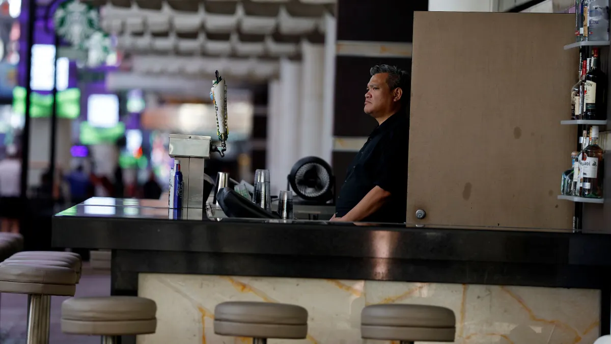 A bartender waits for customers behind a bar.