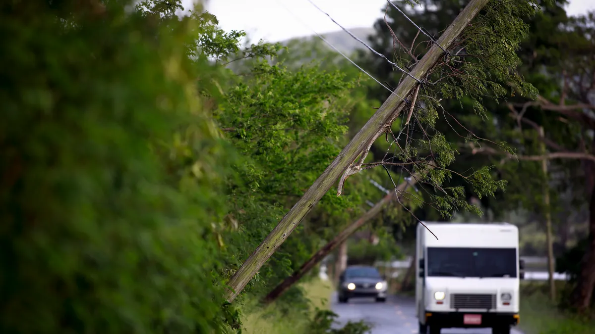 Cars drive through along a road in Lajas, Puerto Rico, next to downed power lines.