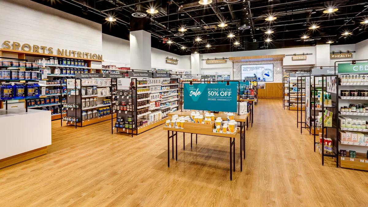 The interior of a store with various displays and wood flooring. Lights are suspended from a black ceiling.