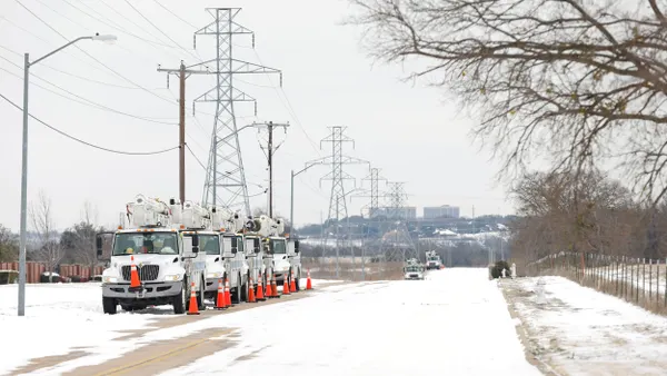 Electric utility trucks and power lines against snow