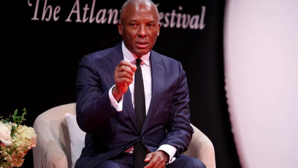 A person in a suit gestures on stage