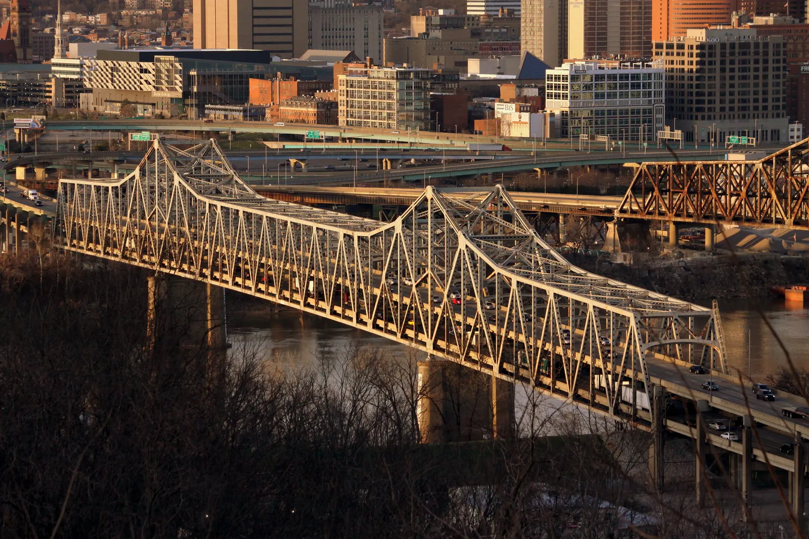 View of a double decker bridge over a river with a city skyline in the background.