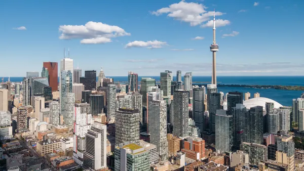 A skyline shot of Toronto, Ontario, with a bright blue sky in the background.